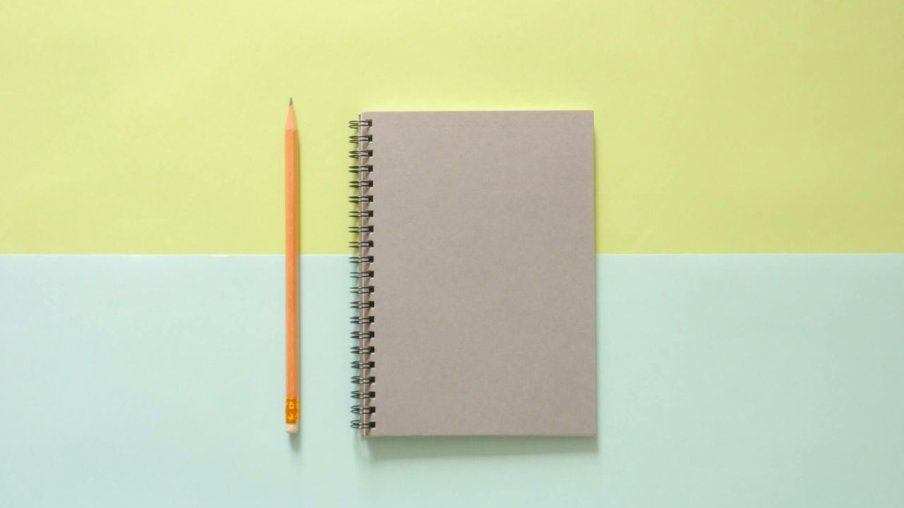 grey notebook next to a yellow, eraser-tipped pencil