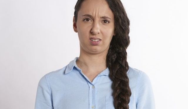 Confused-looking woman with long brown hair, wearing a light blue shirt