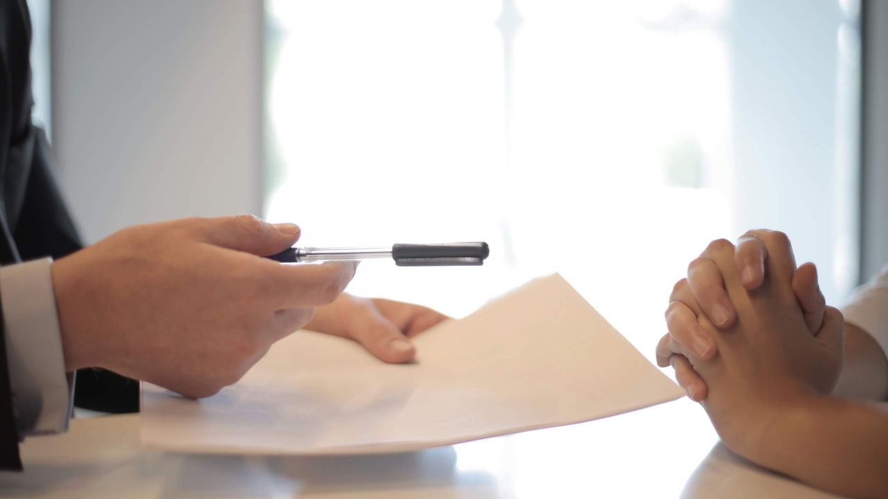 Close-up photo of two pairs of hands over an interview table.