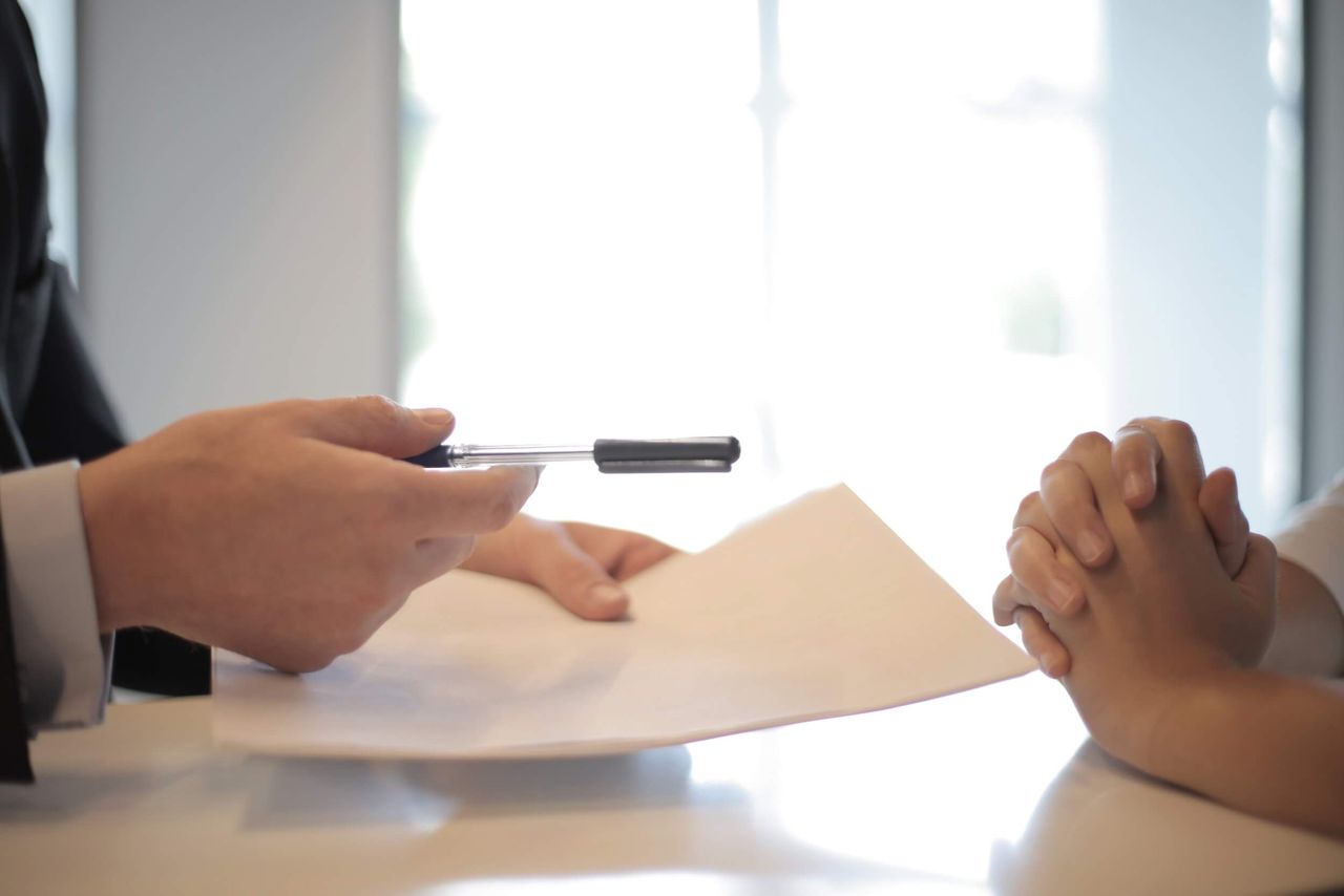 Close-up photo of two pairs of hands over an interview table.