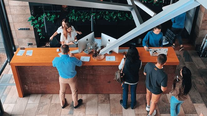 Photo of people checking in at a long hotel reception desk