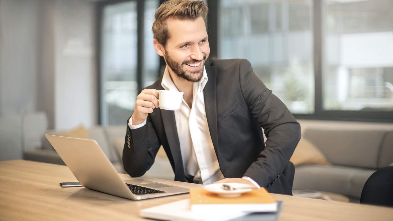 Business man with with open collar and white coffee cup his hand.
