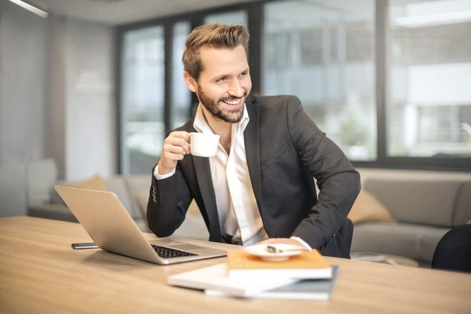 Business man with with open collar and white coffee cup his hand.