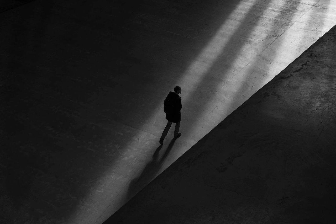 A black and white image, showing a distant silhouette of someone walking away.