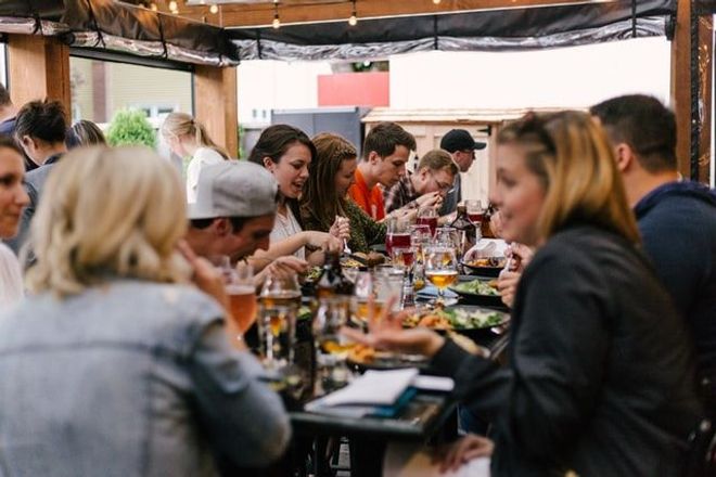 Group of women and men eating and drinking in an outdoor restaurant setting