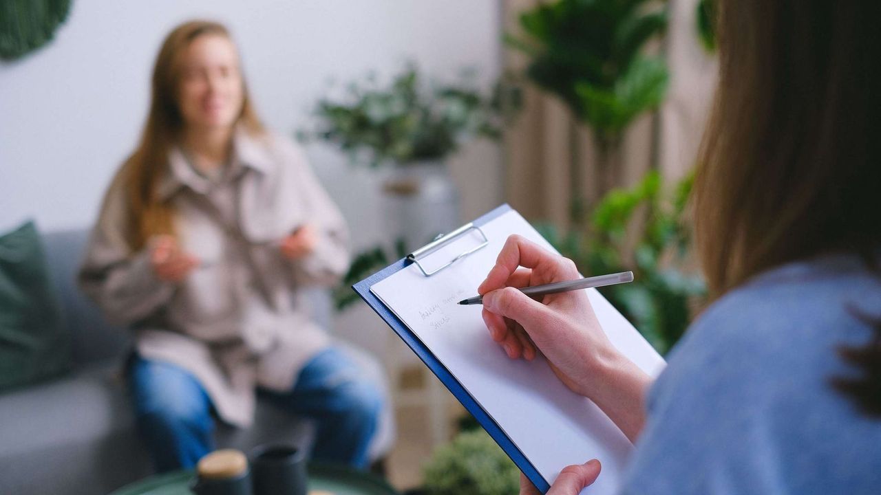 Photo of someone conducting an interview while taking notes on a blue clipboard.