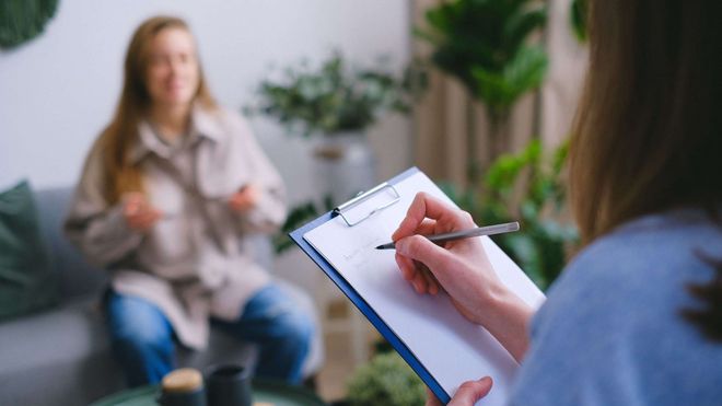 Photo of someone conducting an interview while taking notes on a blue clipboard.