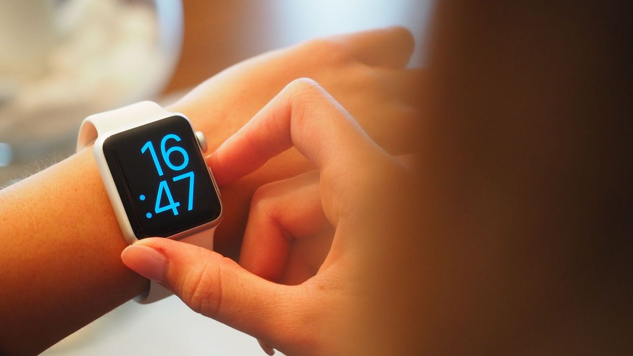 Close up photo of a smartwatch displaying 16:47 on a woman's wrist
