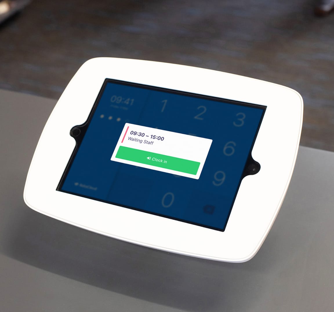 Employee having their photo taken on a clocking in terminal with shift details and 'Clock in' button.