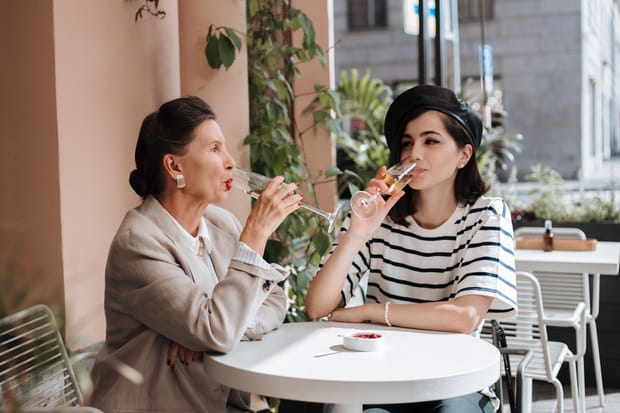 Mother and daughter sipping champagne at at outdoor cafe table
