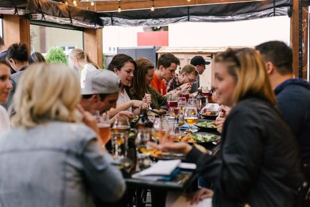 Group of women and men eating and drinking in an outdoor restaurant setting