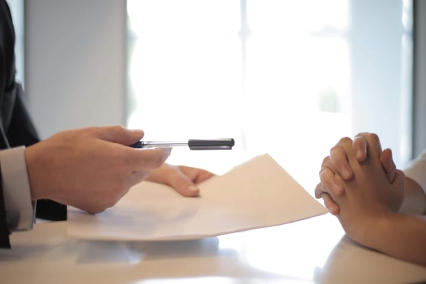 Close-up photo of two pairs of hands over an interview table.