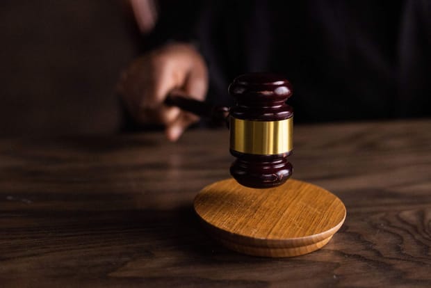 Judge's gavel being tapped on a polished wooden desk.