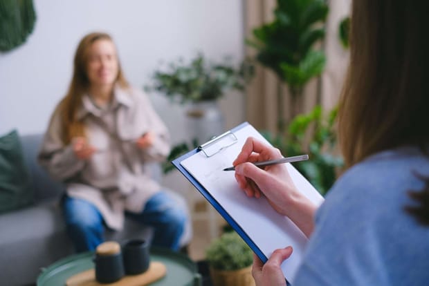 Photo of someone conducting an interview while taking notes on a blue clipboard.