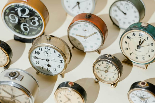 Isometric photo of several old-fashioned alarm clocks displaying different times