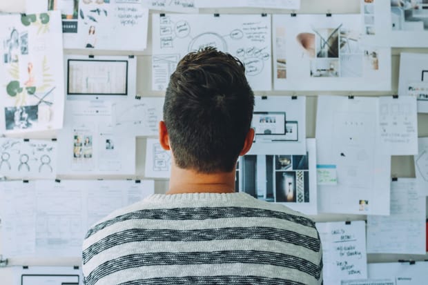 A man looking at a wall filled with plans.