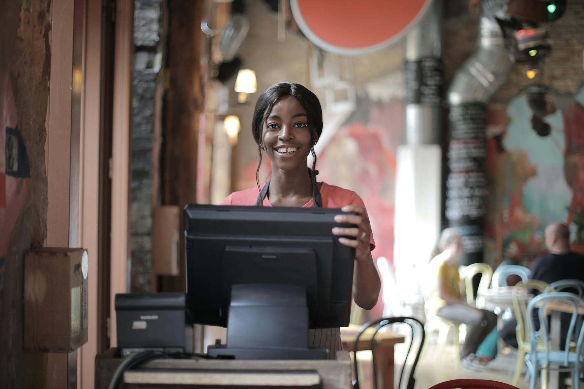 A waitress stood behind the till of the restaurant/bar, smiling, as if ready to take your order.